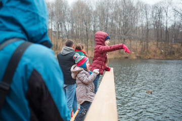 family walks in the Park in autumn. dad with children to feed ducks on lake. people in October outdoors