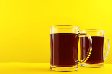 Delicious homemade kvass in glass mugs on yellow background. Space for text