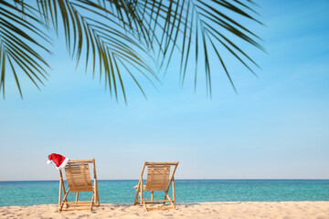 Sun loungers and Santa's hat on beach, space for text. Christmas vacation