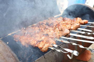 pork meat on a metal skewer is fried