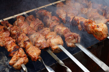 pork meat on a metal skewer is fried
