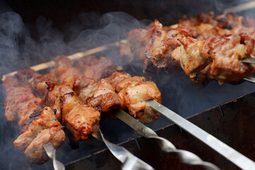 pork meat on a metal skewer is fried