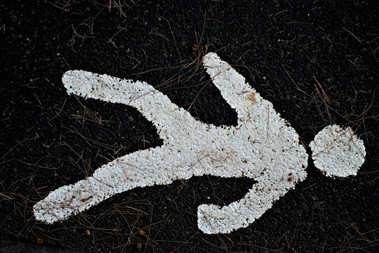 White human figure painted on black background, road signage on tarmac.