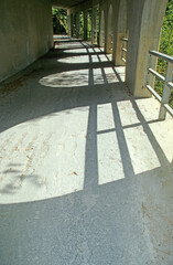 Close up view of mountain tunnel. White concrete with arched sides and metal barriers. Sunshine and shadow pattern on floor. Austria.