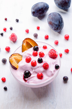 yourt with fruit, plum, berries on a white table