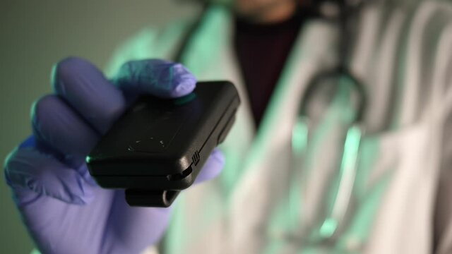 80s 90s vintage pager beeper being used by a doctor or nurse wearing a uniform. The pager is still used today in many medical facilities.