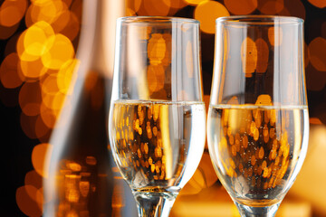 Champagne glass on blurred garland lights background