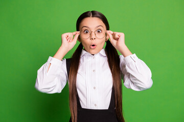 Photo portrait of shocked girl using glasses for the first time isolated on vivid green colored background