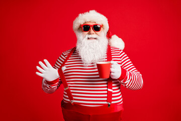 Fototapeta na wymiar Portrait of his he nice handsome attractive cheerful cheery confident Santa father drinking eggnog pulling suspender having fun isolated bright vivid shine vibrant red color background