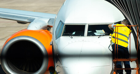 Worker wipes the front cockpit window of the aircraft before flight