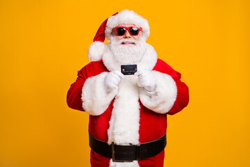 Fototapeta na wymiar Portrait of his he nice attractive cheerful cheery Santa holding in hand bank card spend budget safe shopping isolated bright vivid shine vibrant yellow color background