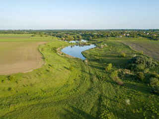 Fototapeta na wymiar Lake among agricultural fields. Aerial drone view.