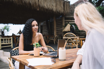 Positive caucasian female student talking about online education project on free time sitting with...
