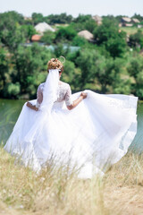 Fototapeta na wymiar Happy bride in a wedding dress, against the backdrop of beautiful nature. Wedding day