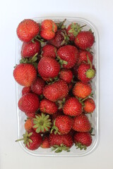 strawberries in a plastic basket on white background