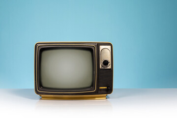 Old retro yellow TV receiver set on white table on blue background