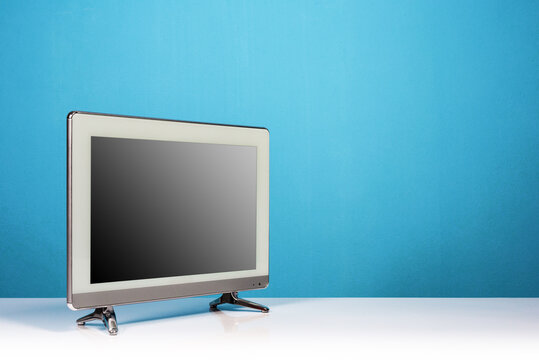 LCD television monitor on white table on blue wall background, flat screen tv