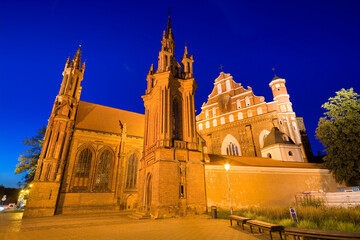Night view of illuminated Gothic style St. Anne Church at Maironio Street in the Old Town of Vilnius, Lithuania. Church of St. Francis and St. Bernard on the right