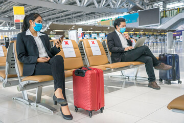 travelers Asian women wearing masks covid 19 disease Prevention An sitting, creating a social distancing while waiting check in with smartphone in the airport terminal