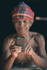 Asian older man using cell phone in the countryside, Thailand.