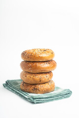 A Stack Of Four Freshly Baked Bagels On A Green Napkin