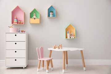 Children's room interior with house shaped shelves and little table