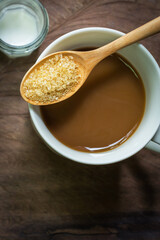 Cup of coffee with brown sugar and milk on wooden background.