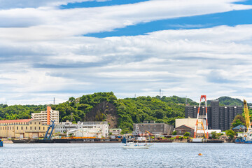 yokosuka, japan - july 19 2020: Fishing boat moored in front of the warehouses and deck barges or crane barges of the Nagaura port in the Yokosuka Naval Base.