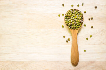 Mung beans for cooking in wooden spoon on wooden board ; Food background with copy space.