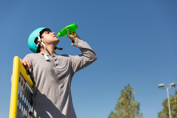 roller boy drinking water in a bottle in a skate park