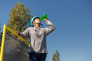 roller boy drinking water in a bottle in a skate park