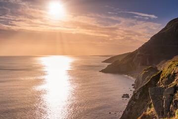 Dramatic sunrise with sun star on a Cliff Walk between Bray and Greystones with beautiful coastline, train tracks, cliffs and Irish Sea, Ireland