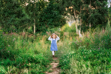 beautiful little girl on a walk in the summer forest
