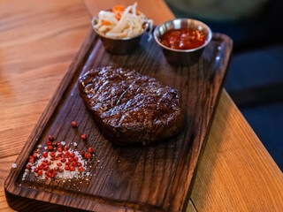 grilled beef steaks with spices on wooden cutting board. shallow depth of field