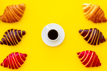 Coffee and croissants on yellow background top view