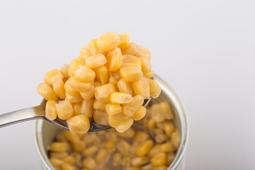 Open metallic can with sweet corn on a white background.