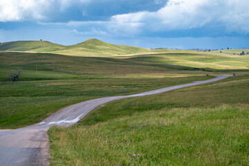 Minimalist landscape photo of a winding road at Custer State Park with blue sky clouds