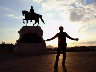Silueta de hombre y atardecer junto a estatua