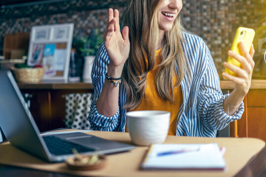 Distance Learning Online Education And Work. Business Woman Having A Facetime Video Call. Happy And Smiling Girl Working From Home Office Kithcen And Drinking Coffee. Using Computer And Mobile Phone.