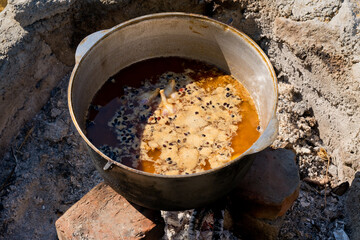 Cooking pilaf in a large cauldron over an open fire. Close-up.