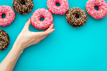 Hand holding donut with icing and sprinkles. Flat lay, top view