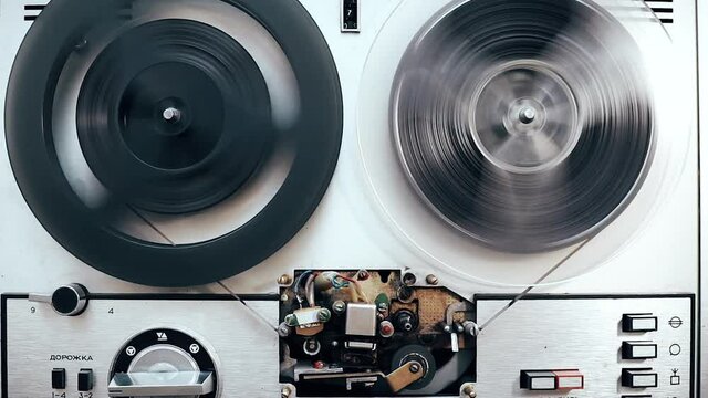 vintage bobbin tape recorder rewinding tape, top view, grunge atmosphere close up. fusty old technology