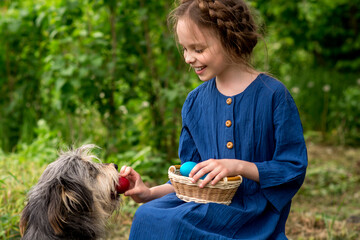 Little smiling girl with Easter colored eggs  playing with big pet dog.