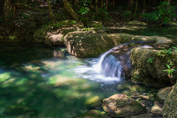 Naklejka na ściany i meble Clear stream that flows through the rocks. Falling into the Emerald Pool, Erawan Kanchanaburi, Thailand.