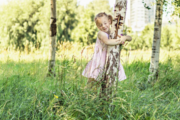 Little girl with a bouquet of wildflowers in her hands by the tree