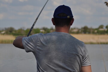 young guy fisherman with a fishing rod on the shore