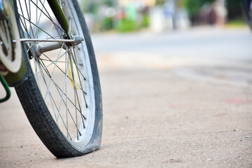 The rear wheel of the bicycle is flat and is left parked on the sidewalk to change and fix it.