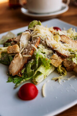Appetizing Caesar salad with chicken breast in a plate on the table. Close-up. Vertical.