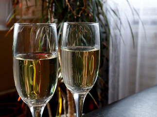 Beautiful two glasses of champagne standing on the table against the background of a blurred room in the interior. Soft focus. Shallow depth of field.