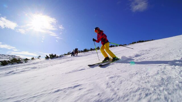 intermediate female skier skiing on slopes on a sunny day.